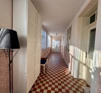 Chodba v rodinném domě s vzorovanou dlažbou a černou lampou.