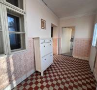 Chodba v rodinném domě s dlaždicovou podlahou a bílým nábytkem.