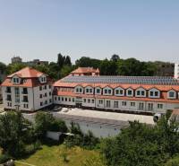 Budova na Sadové ulici v Senici s červenou střechou a solárními panely.