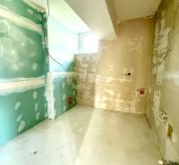 Je nedokončená místnost v 2-pokojovém bytě s holými stěnami a oknem.