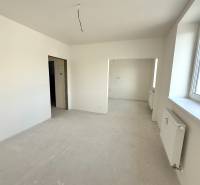 Světlý pokoj, prostorné okno, bílé stěny a radiátor v 2-pokojovém bytě.