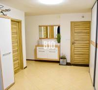 Interiér rodinného domu s dřevěnými dveřmi, zrcadlem a dlažbou.