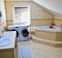 Koupelna s vanou, dvěma umyvadly, pračkou a sušičkou v rodinném domě.