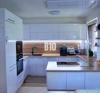 Kuchyně v rodinném domě se zabudovanými spotřebiči, varnou deskou a dřevěnou pracovní deskou.