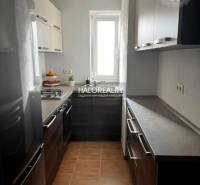 Kuchyně ve 3-pokojovém bytě s moderními skříňkami, sporákem, světlými stěnami, keramickou podlahou.