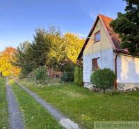 Chatka v Sološnici u cesty, obklopená stromy a trávníkem během podzimu.