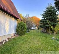 Podzim v Sološnici u chaty, obklopené zelení a jehličnany.