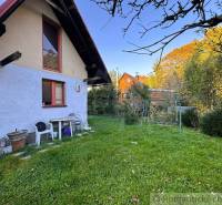 Exteriér chaty v Sološnici obklopený zeleným trávníkem a stromy.