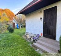 Chata v Sološnici s trávníkem a stromy v barevné podzimní krajině.