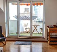 Obývací pokoj s balkonem, dřevěná podlaha, židle a stolek ve 3pokojovém bytě.