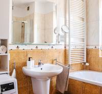 Koupelna v 3-pokojovém bytě s umyvadlem, vanou, pračkou a sušákem na ručníky.