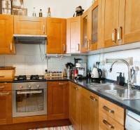 Kuchyně s dřevěnými skříňkami a spotřebiči v 2pokojovém bytě.