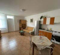 Interiér rodinného domu s kuchyňským koutem a podlahou s dřevěným dekorem.