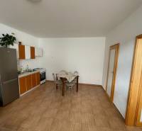 Kuchyně v rodinném domě s dlažbou a jídelním stolem.