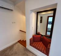 Rodinný dům zobrazuje schody s dřevěným dekorem, zrcadlo a sedací koutek s polštáři.