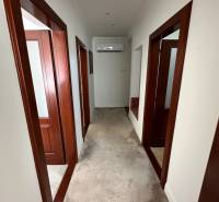 Chodba v rodinném domě s bílými stěnami, kobercem a dřevěnými zárubněmi.