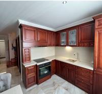 Kuchyně s tmavými dřevěnými skříňkami a podlahou s dřevěným dekorem v rodinném domě.