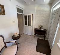 Jídelna v rodinném domě se stropem s reliéfy a ornamentální podlahou, stůl a křeslo.