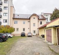 Budova na Bratislavské ulici v Žilině, obklopená auty a garážemi, vhodná pro kanceláře.