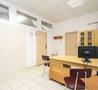 Kanceláře se stolem, židlí, počítačem a skříní na světlé keramické podlaze.