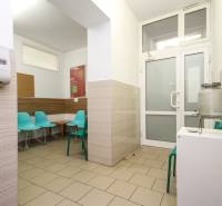 Čekárna v kanceláři s tyrkysovými židlemi a nádobou na vodu.