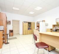 Kanceláře s bílými stěnami, dřevěným nábytkem a keramickou podlahou.