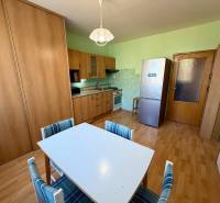 Kuchyně v 1-pokojovém bytě s podlahou s dřevěným dekorem a jídelním stolem.