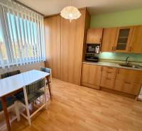 Kuchyně v 1-pokojovém bytě s podlahou s dřevěným dekorem a jídelním stolem.