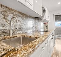 Kuchyně s kamennou pracovní deskou a podlahou s dřevěným dekorem v 3-pokojovém bytě.