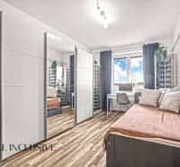 Pokoj se zrcadlovou skříní, pracovním stolem a podlahou s dřevěným dekorem ve 3pokojovém bytě.