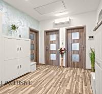 Interiér 3-pokojového bytu s podlahou s dřevěným dekorem a bílým nábytkem.