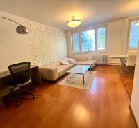 Obývací pokoj ve 3-pokojovém bytě s pohovkou, stolkem a pracovním stolem.