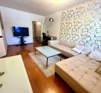 Obývací pokoj s béžovou sedačkou a televizorem v 3pokojovém bytě.