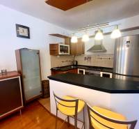 Kuchyně v 3pokojovém bytě s barovým pultem, kovovými židlemi a elegantními lampami.