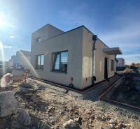 Rodinný dům v Hubicích ve výstavbě s neupraveným terénem. Jasná obloha a sluneční světlo.