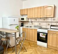 Kuchyně v garsonce s podlahou s dřevěným dekorem, se spotřebiči a sezením.