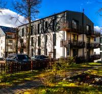 Exteriér bytového domu na Lúčnej ulici v Štrbě s zaparkovanými vozidly a upraveným okolím.