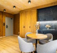 Interiér 2-pokojového bytu s podlahou s dřevěným dekorem, dřevěnými stěnami a černou kuchyňskou linkou.