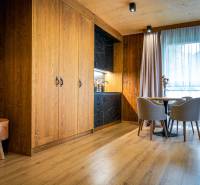 Pokoj v 2pokojovém bytě s kuchyňským koutem, dřevěnými stěnami a podlahou s dřevěným dekorem.