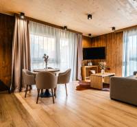 Obývací pokoj v 2-pokojovém bytě s podlahou s dřevěným dekorem, sedačkou a jídelním stolem.