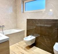 Koupelna v rodinném domě s vanou, umyvadlem, bidetem a podlahou s dřevěným dekorem.