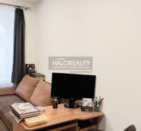 Obývací pokoj s pohovkou, stolkem a podlahou s dřevěným dekorem ve 3pokojovém bytě.