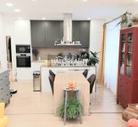 Kuchyně ve 3-pokojovém bytě s podlahou s dřevěným dekorem, jídelní stůl a knihovna.