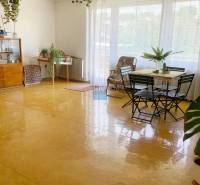 Prostorný světlý obývací pokoj, podlaha s dřevěným dekorem, nábytek a rostliny v rodinném domě.