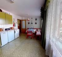 Kuchyně v rodinném domě s retro nábytkem, stolem, velkým oknem a dekoracemi.