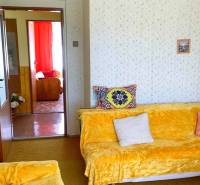 Obývací pokoj v rodinném domě s barevnými dekami a polstrováním na sedačkách.