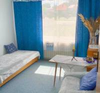 Pokoj v rodinném domě s modrými závěsy, pohovkou a postelí.