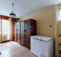 Interiér rodinného domu s mrazničkou, skříňkami a velkým oknem.