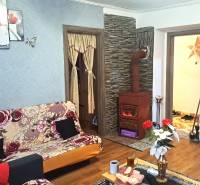 Obývací pokoj v 2-pokojovém bytě s kachlovými kamny a podlahou s dřevěným dekorem.