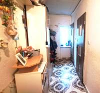 Chodba s skříňkami a dekoracemi v 2-pokojovém bytě. Vlevo věšáky, vpravo dveře.